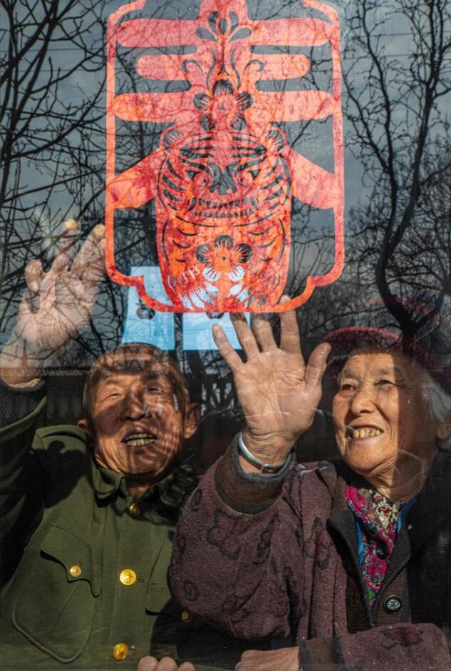 臘月里，霍州市師莊鄉(xiāng)馮南垣村村民師榮光(左)在災(zāi)后重建的新家里貼窗花。(霍州市委宣傳部供圖)