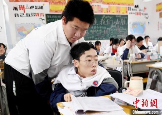 朱金祥(左)把鐘華強放到課堂座位上后，都要把他擺正好，確認(rèn)安全后才回到自己的座位上。 卓忠偉 攝