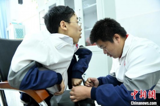 江西省南康中學(xué)北校區(qū)的高三學(xué)生朱金祥(右)正在給鐘華強(左)系好鞋帶。 卓忠偉 攝