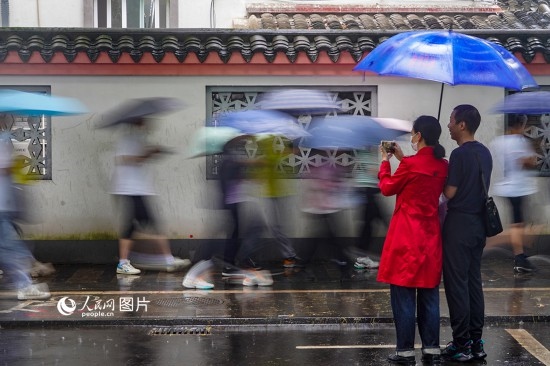 6月7日，在浙江省2023年普通高校招生考試鎮(zhèn)海中學考點，家長冒雨目送子女進入考場。人民網(wǎng) 章勇濤攝