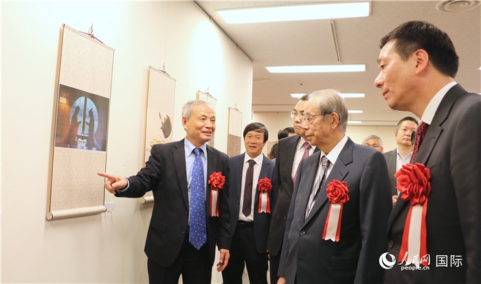 “湖州印象”攝影展主創(chuàng)、世界華人攝影協(xié)會副會長馮學敏向吳江浩大使、福田康夫前首相等嘉賓介紹展出作品。（人民網(wǎng) 許可攝）