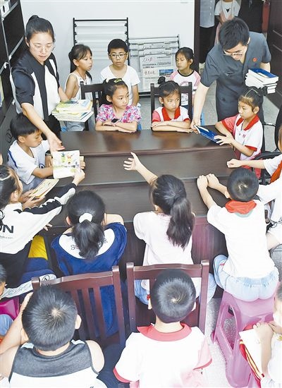  圖④：法院干警為留守兒童發(fā)放暑假讀物。