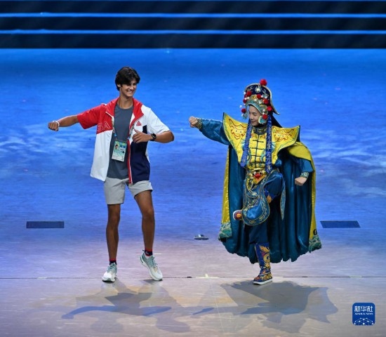 7月29日，美國運動員杜恩（左）在聯(lián)歡會現(xiàn)場與川劇演員互動。新華社記者 蔡湘鑫 攝