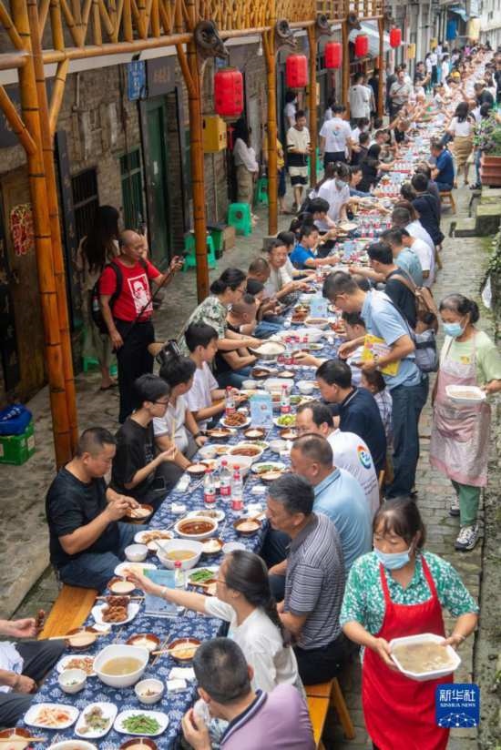 7月29日，在重慶市綦江區(qū)安穩(wěn)鎮(zhèn)，人們在“苗家伏羊節(jié)”上吃長桌宴。新華社記者 唐奕 攝