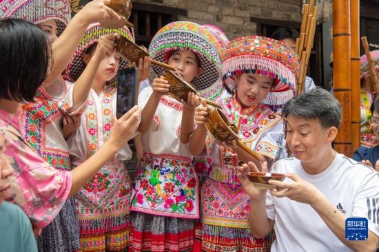 7月29日，在重慶市綦江區(qū)安穩(wěn)鎮(zhèn)，當(dāng)?shù)鼐用裨凇懊缂曳蚬?jié)”上用傳統(tǒng)習(xí)俗向游客表達祝福。新華社記者 唐奕 攝