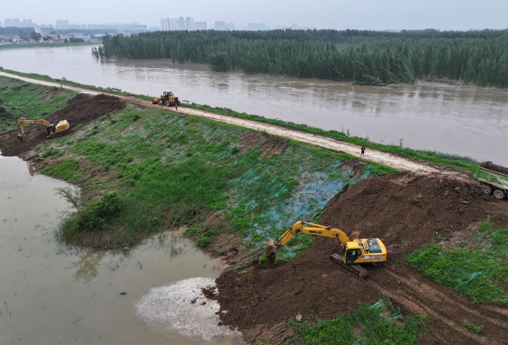 工人操作機械在白溝河左堤白溝新城高橋村段進行除險加固作業(yè)（8月4日攝，無人機照片）。新華社記者 朱旭東 攝