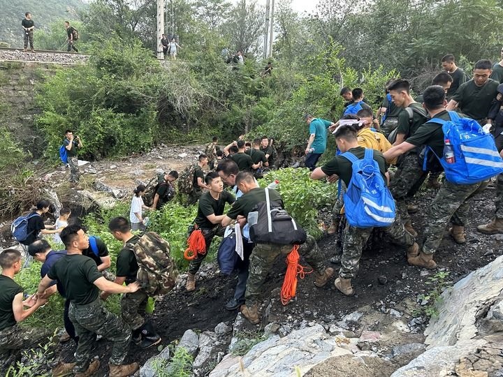 8月2日，Z180次受困列車的旅客在武警北京總隊機動第三支隊官兵的幫助下徒步前往轉(zhuǎn)運客車（手機照片）。新華社記者 王艷剛 攝