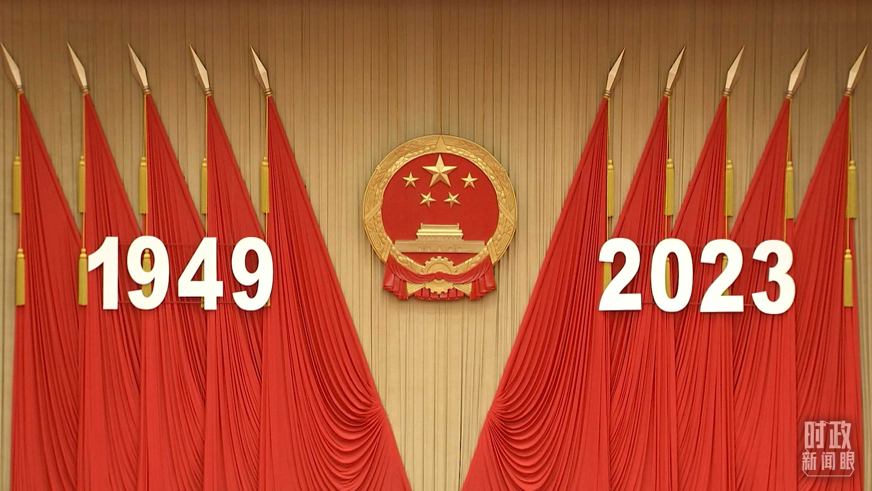 △人民大會(huì)堂宴會(huì)廳內(nèi)，主席臺(tái)上方高懸著莊嚴(yán)的國徽，“1949－2023”大字年號(hào)在鮮艷的紅旗映襯下格外醒目。