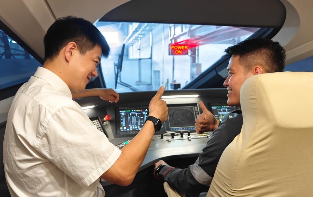 8月25日，在印度尼西亞萬隆的雅萬高鐵德卡魯爾動車所內(nèi)，中國師傅穆振（左）在向印尼火車司機塞蒂亞萬講解動車組出庫前的上電作業(yè)。