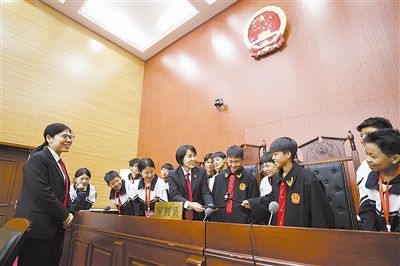 圖③：同學(xué)們穿法袍、敲法槌，爭做“小法官”。