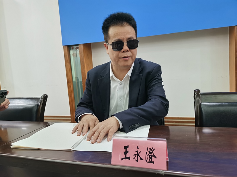 全國(guó)人大代表王永澄正在閱讀盲文版代表建議答復(fù)。本報(bào)記者 張 璁?dāng)z