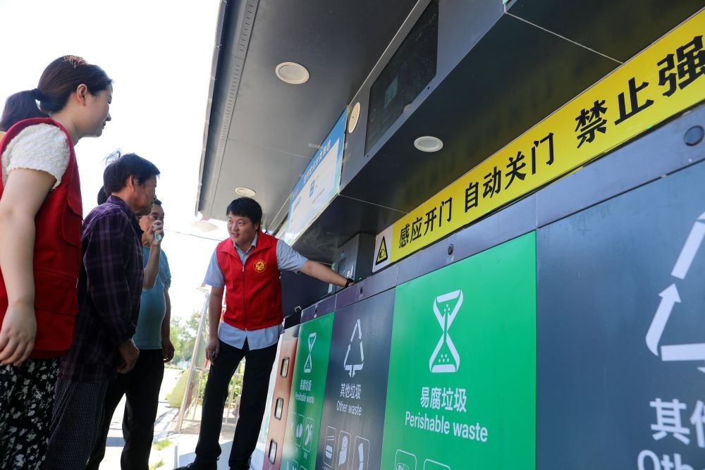 在安徽省合肥市長豐縣莊墓鎮(zhèn)棗林社區(qū)，志愿者指導(dǎo)居民使用智能垃圾分類回收設(shè)備（2023年9月1日攝）。新華社記者 曹力 攝