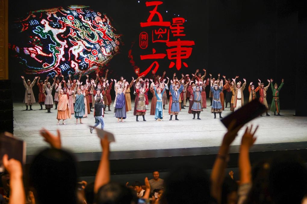 2023年7月31日，新疆和田地區(qū)新玉歌舞團在烏魯木齊京劇院演出舞劇《五星出東方》后和觀眾互相揮手致意。這場演出是第六屆中國新疆國際民族舞蹈節(jié)的參演劇目之一，曾榮獲國家“文華獎”等。新華社記者 郝昭 攝