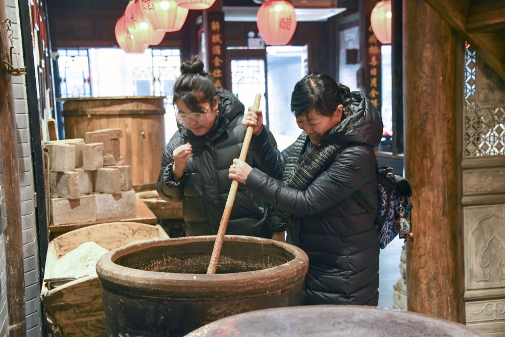 游客在平遙古城東湖老醋坊內(nèi)體驗陳醋發(fā)酵打耙（2022年1月28日攝）。新華社發(fā)（梁生仁攝）