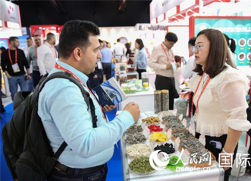 圖為一家中國干果參展企業(yè)代表與采購商洽談。人民網(wǎng) 塔里克·易卜拉欣攝