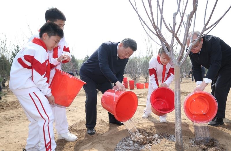 2024年4月3日，習(xí)近平總書記同少先隊員一起給剛栽下的樹苗澆水。