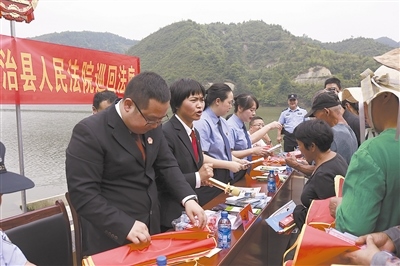 法院干警及相關(guān)部門工作人員對群眾進行生態(tài)環(huán)境保護普法教育。