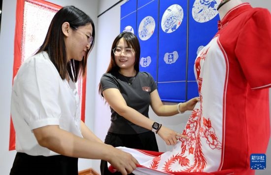 5月31日，在衡水市阜城縣一家剪紙工作室，游客在觀賞帶有剪紙?jiān)氐钠炫邸? width=