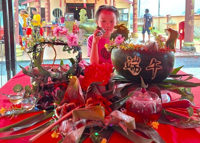 小朋友展示學(xué)裹粽子的成品照。組委會供圖