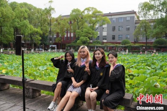 6月19日，時(shí)值一年畢業(yè)季，四川大學(xué)望江校區(qū)荷花池里的荷花盛開，成為了畢業(yè)生們的打卡圣地，吸引了眾多畢業(yè)生拍照留念。圖為畢業(yè)生在荷花池邊拍照留念。中新社記者 安源 攝