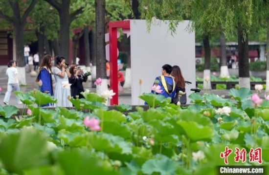 6月19日，時(shí)值一年畢業(yè)季，四川大學(xué)望江校區(qū)荷花池里的荷花盛開，成為了畢業(yè)生們的打卡圣地，吸引了眾多畢業(yè)生拍照留念。圖為畢業(yè)生在荷花池邊拍照留念。中新社記者 安源 攝