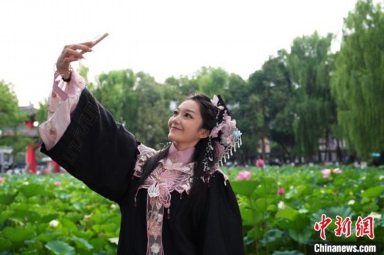 6月19日，時(shí)值一年畢業(yè)季，四川大學(xué)望江校區(qū)荷花池里的荷花盛開，成為了畢業(yè)生們的打卡圣地，吸引了眾多畢業(yè)生拍照留念。圖為畢業(yè)生在荷花池邊拍照留念。中新社記者 安源 攝