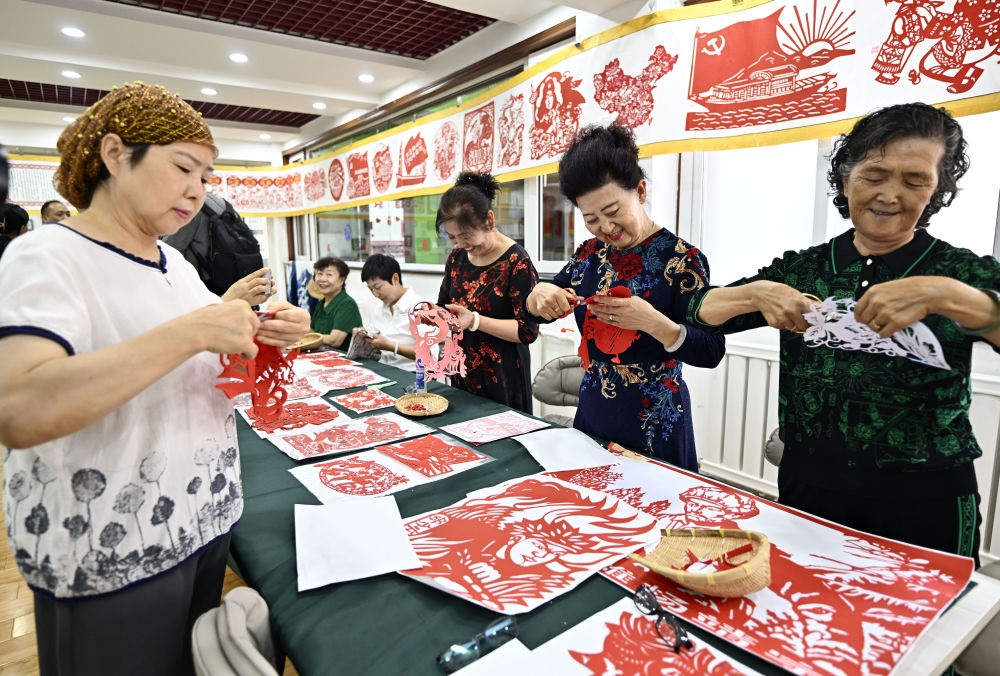6月19日，長城花園社區(qū)居民在社區(qū)“才藝堂”制作剪紙。