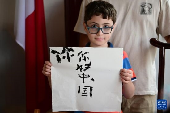 7月4日，在馬耳他桑塔露琪亞市的中國古典園林“靜園”，一名男孩展示他的書法作品。新華社發(fā)（喬納森·博格 攝）