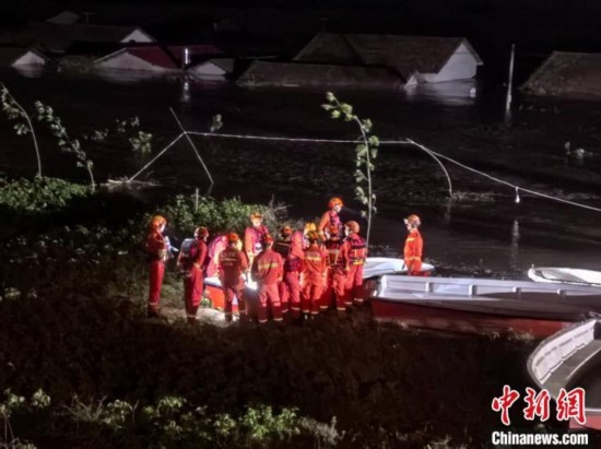  7月6日凌晨3時(shí)，在湖南岳陽(yáng)華容縣團(tuán)洲垸洞庭湖一線堤防，救援人員剛剛完成一次救援任務(wù)，遠(yuǎn)處是被淹的民房。中新社記者 白祖偕 攝
