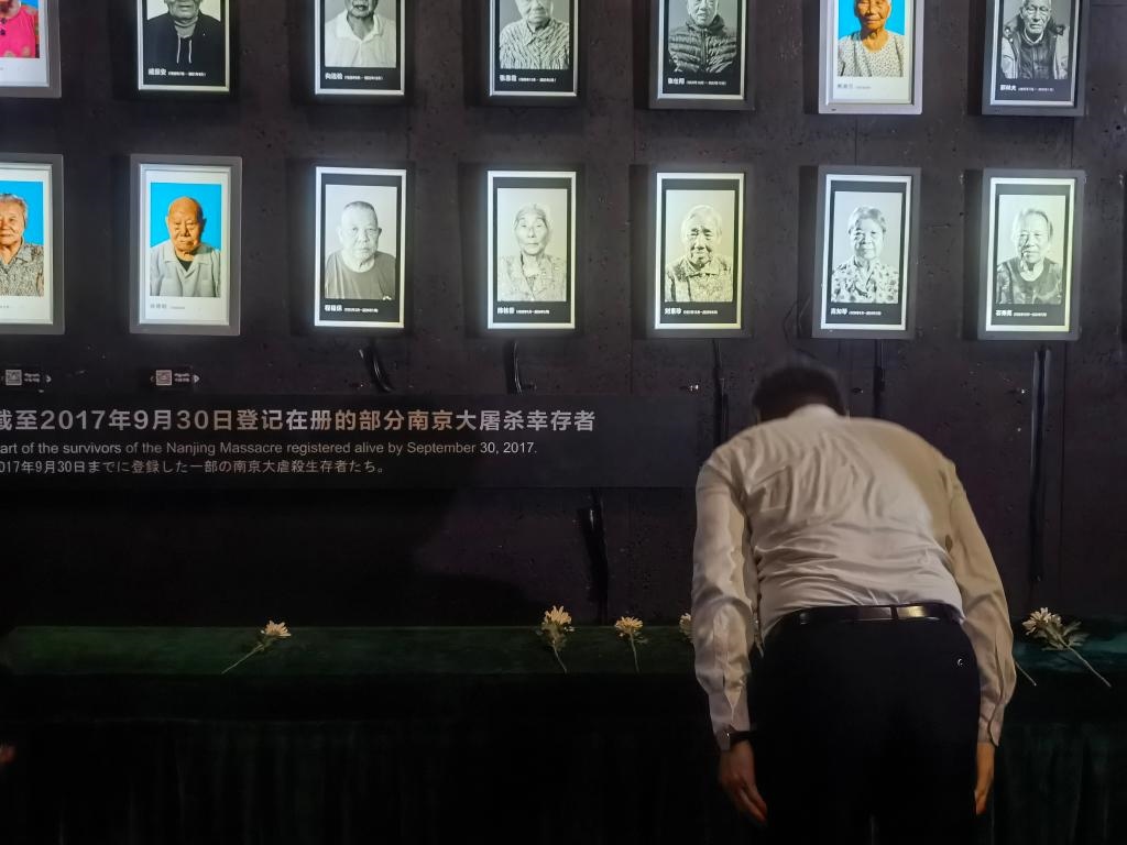7月18日，人們向離世的南京大屠殺幸存者獻(xiàn)花、鞠躬。新華社記者邱冰清 攝