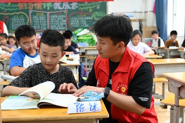 鄭州市二七區(qū)暑托班的志愿者輔導(dǎo)孩子寫(xiě)作業(yè)。人民網(wǎng)記者王玉興攝
