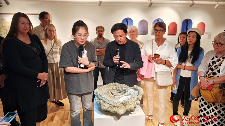 參展人、景德鎮(zhèn)陶瓷大學(xué)設(shè)計(jì)藝術(shù)學(xué)院副院長(zhǎng)余劍峰（中）向來(lái)賓介紹參展作品。人民網(wǎng)記者 殷淼攝
