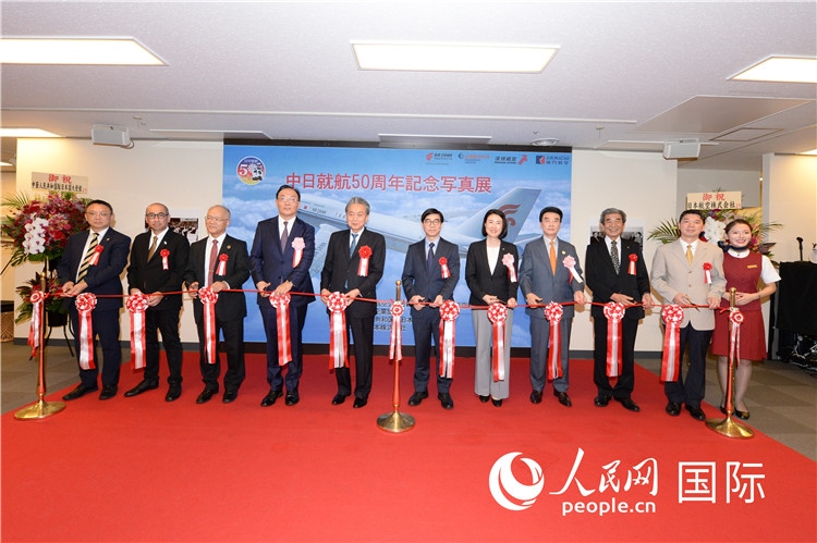與會(huì)嘉賓共同為中日通航50周年紀(jì)念圖片展開幕剪彩。馮學(xué)敏攝
