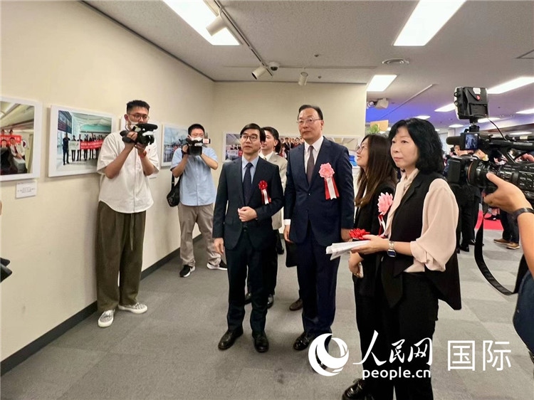 中國國際航空日韓地區(qū)支社支社長(zhǎng)馮力為中國駐日本大使館臨時(shí)代辦施泳等嘉賓介紹展出圖片。人民網(wǎng) 許可攝