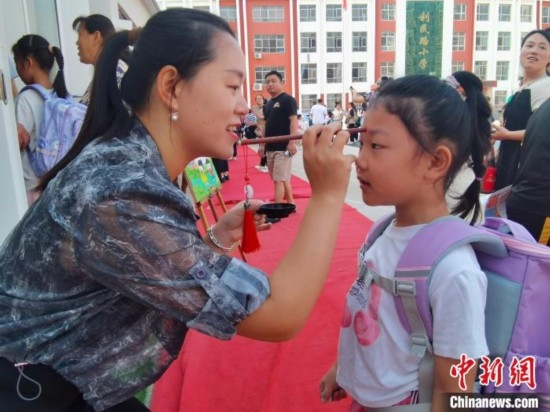 圖為衡水市利民路小學(xué)，老師為學(xué)生點(diǎn)朱砂痣，寓意開(kāi)啟智慧。張松 攝