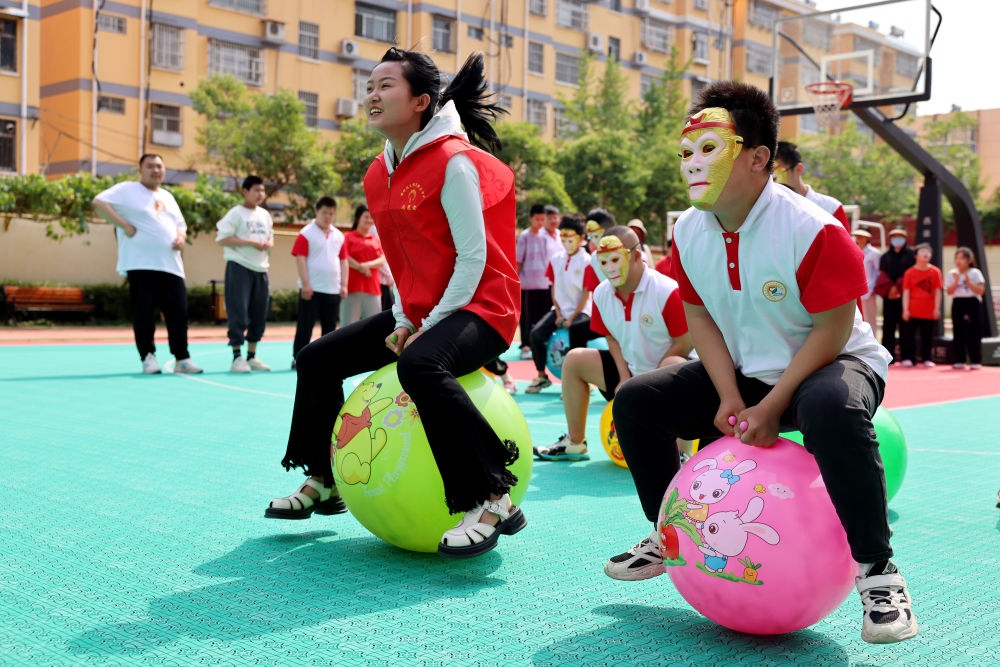 2024年5月17日，在山東省棗莊市市中區(qū)特殊教育中心，青年志愿者與智力障礙學(xué)生一起做游戲。新華社發(fā)（孫中喆攝）