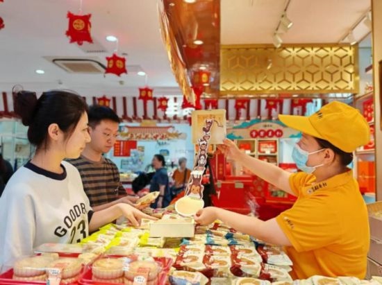 北京稻香村一家門(mén)店內(nèi)，售貨員向顧客展示新上市的月餅禮盒。（受訪(fǎng)者供圖）