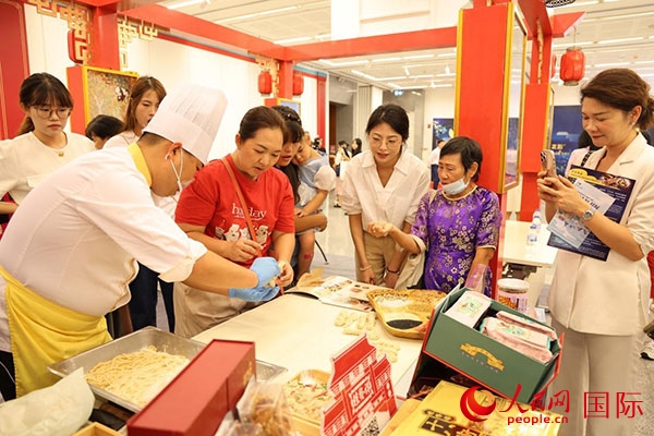 演出前，在天津桂發(fā)祥十八街麻花制作技藝非遺體驗展臺前，泰國民眾體驗天津麻花制作。人民網(wǎng)記者 楊一攝