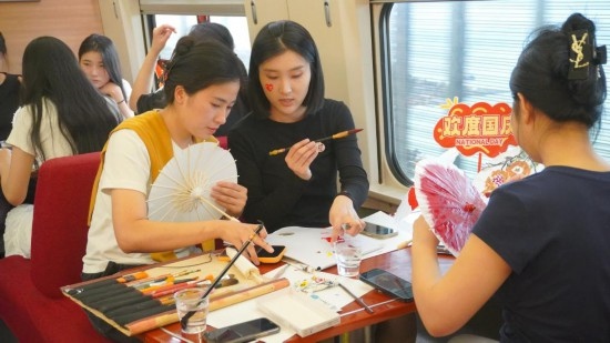 10月1日，旅客們在G1634次列車上給油紙傘作畫。新華社記者周義 攝
