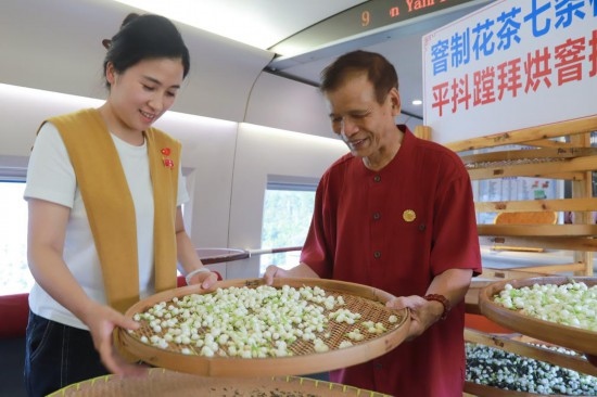 10月1日，福州市茉莉花茶窨制工藝代表性傳承人張子建與旅客在G1634次列車上制作茉莉花茶。新華社記者周義 攝