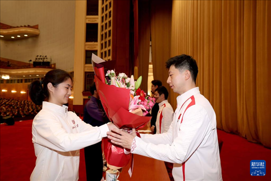 11月15日，一名學(xué)生代表在報(bào)告會上向乒乓球運(yùn)動員馬龍（右）獻(xiàn)花。新華社記者 李明 攝