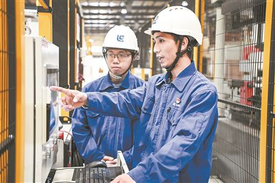 在廣西柳工機(jī)械股份有限公司生產(chǎn)車間內(nèi)，一名高級(jí)技師（右）給徒弟講解數(shù)控設(shè)備操作細(xì)節(jié)。新華社記者 曹祎銘攝