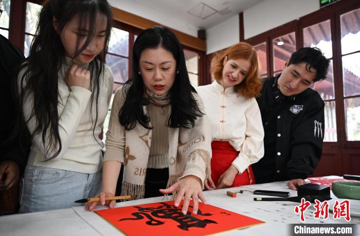1月20日，西泠印社社員李硯（左二）為外籍留學(xué)生講述蛇年福字貼創(chuàng)作靈感。當(dāng)日，來(lái)自巴西、馬來(lái)西亞、加納、哈薩克斯坦的外籍留學(xué)生在浙江杭州西泠印社體驗(yàn)福貼、春聯(lián)和篆刻，感受古老的中國(guó)傳統(tǒng)文化。中新社記者 王剛 攝