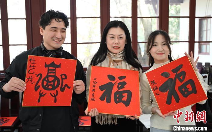 1月20日，外籍留學(xué)生和西泠印社社員李硯(中)展示各自創(chuàng)作的福貼。當(dāng)日，來(lái)自巴西、馬來(lái)西亞、加納、哈薩克斯坦的外籍留學(xué)生在浙江杭州西泠印社體驗(yàn)福貼、春聯(lián)和篆刻，感受古老的中國(guó)傳統(tǒng)文化。中新社記者 王剛 攝