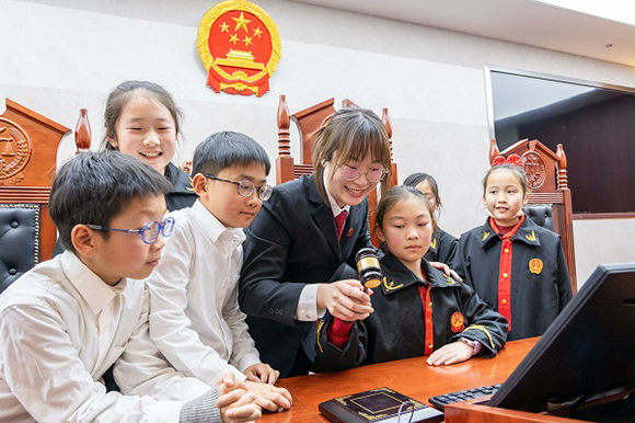 圖①：干警帶同學(xué)們體驗(yàn)敲法槌。