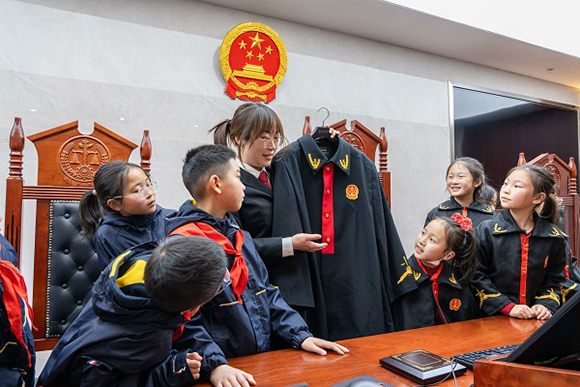圖②：干警向同學(xué)們介紹法袍。