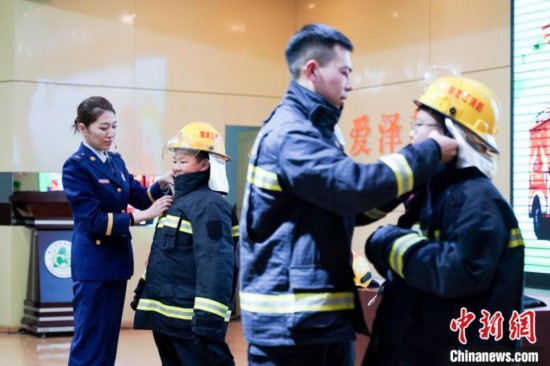 圖為學生們現(xiàn)場穿戴消防頭盔和戰(zhàn)斗服。中新社記者 趙宇航 攝