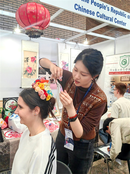 展覽正值羅馬尼亞迎春花節(jié)，國(guó)際中文教師志愿者潘婧穎向游客們介紹了國(guó)家非物質(zhì)文化遺產(chǎn)——福建泉州的簪花文化。布加勒斯特大學(xué)孔子學(xué)院供圖。