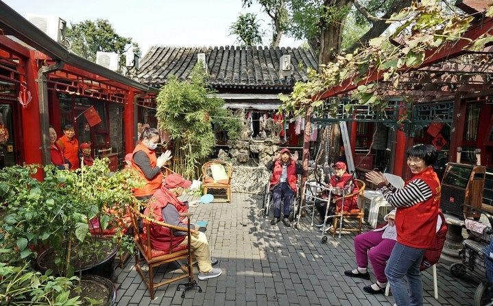 2024年10月12日，鐘樓灣胡同的老年人在社區(qū)內(nèi)的四合院養(yǎng)老驛站休閑。2017年起，北京市先后開展了兩輪背街小巷環(huán)境整治提升行動，完整保留了中軸線生活建筑群的歷史信息，并根據(jù)居民的生活和居住方式進(jìn)行適配化的更新和改造，極大地改善了生活環(huán)境。2023年鐘樓灣胡同被評為“北京最美街巷”。